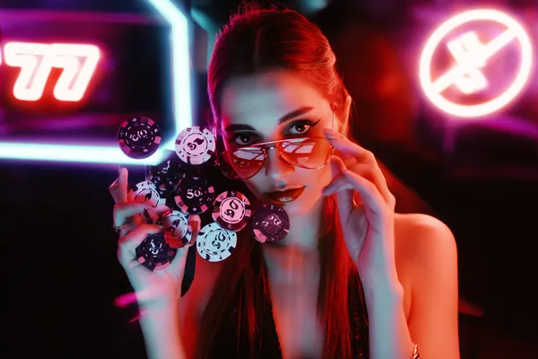 A glamorous woman holding casino chips in a neon-lit environment, representing the premium online casino atmosphere of 599JILI.
