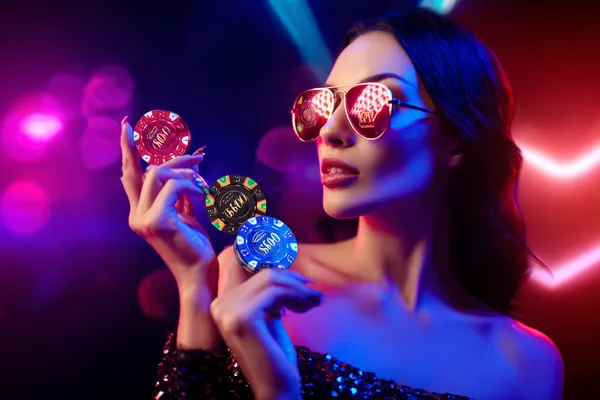 A woman smiling while playing online games on her laptop, surrounded by neon casino elements, showcasing 599JILI’s diverse game collection.